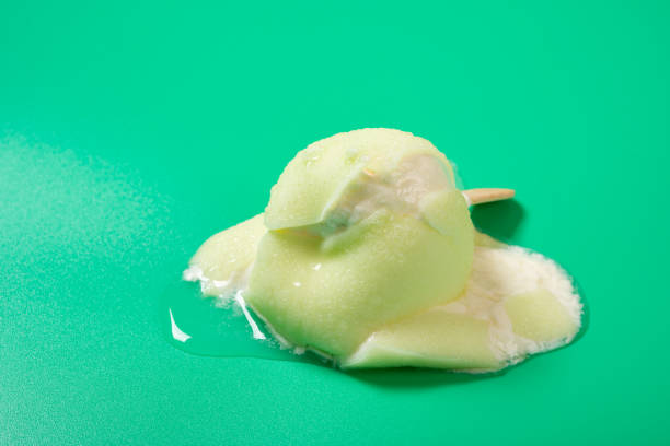 half melted green apple shape and flavor popsice on green background