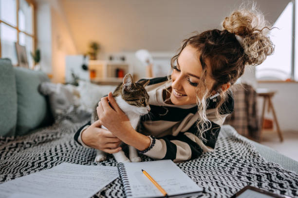 istock Young beautiful female student bonding with her cat while taking a break from studying 1452689814
