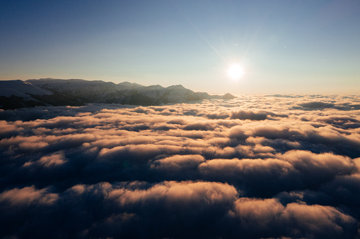 Caucasian mountains above the clouds at the sunset. Cloudscape, aerial view.