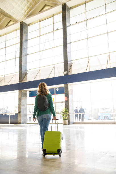 istock Woman dragging her green suitcase and exiting a train station 1452690619