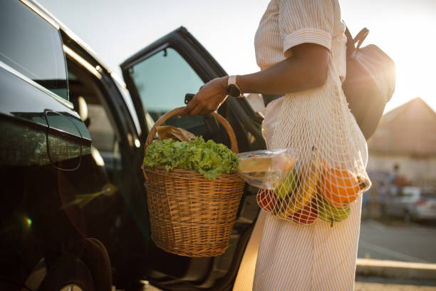 woman loading groceries in a wooden basket in the back seat of her car - car car door green part of imagens e fotografias de stock
