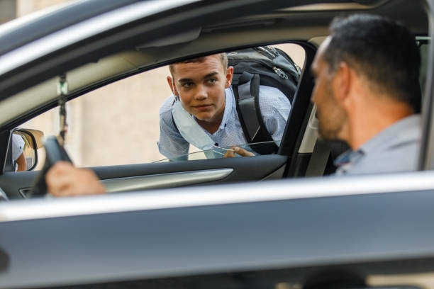 Man saying hi to his teeange son that he is picking up from school stock photo