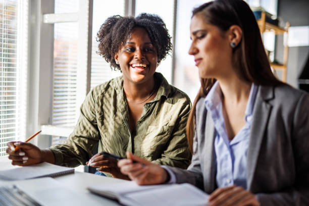 Two cheerful young businesswomen co-working on a project together