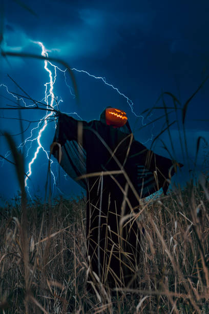 istock A scary scarecrow with a pumpkin head in a night corn field during a thunderstorm. 1452693145