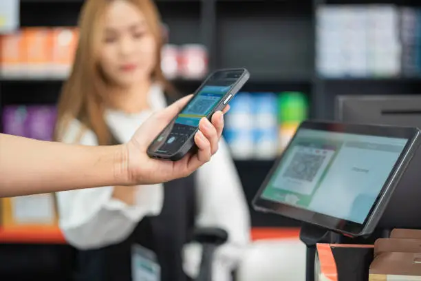 close up hand holding phone to scan to pay at checkout in a supermarket