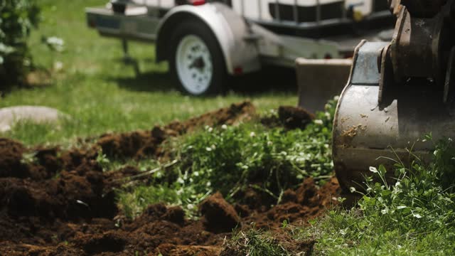 Excavator bucket cutting through grass to fresh dirt (4k 30p Slow Motion)