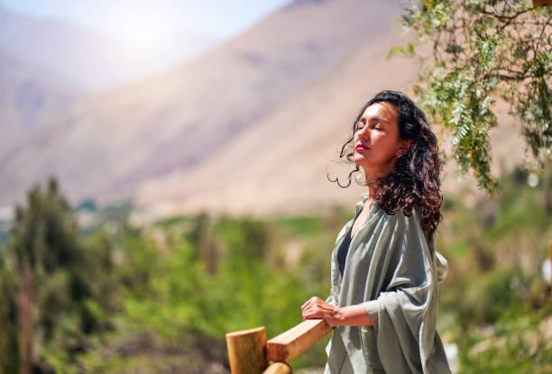 mid adult latin woman with eyes closed and head raised enjoying the sun and the breeze in Paihuano, Valle del Elqui stock photo
