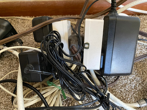 A tangled mess of household electrical cords plugged into the same power adapter.