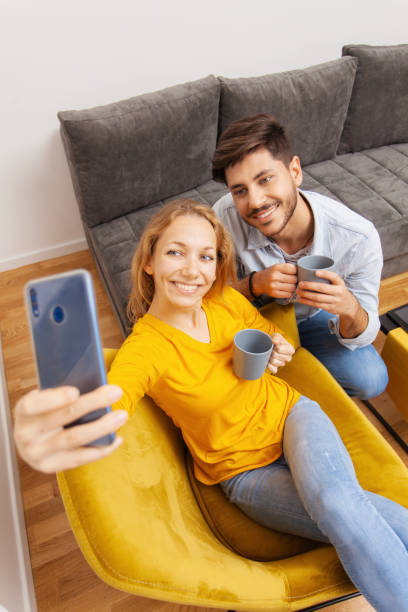 istock couple drinking coffee and taking selfie 1452699023
