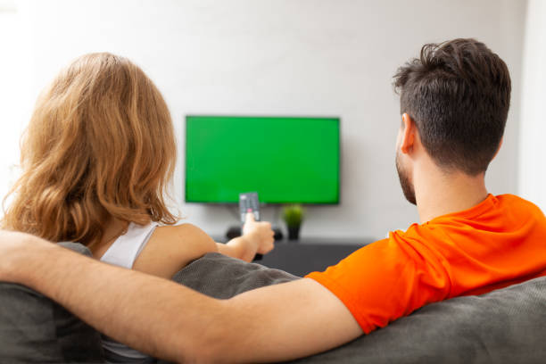 istock Couple watching tv with green screen. Girl pressing remote control. 1452699197