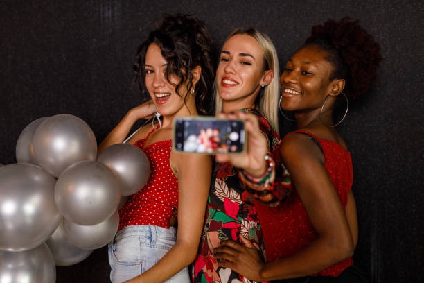istock Two joyful girlfriends taking selfies with smart phone during a New Year's eve party celebration 1452700704