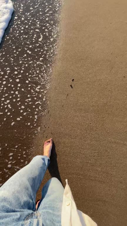 Barefoot woman walking alone on the beach,  first person view