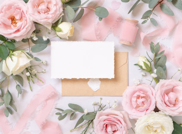 istock Blank card and envelope between pink roses and silk ribbons top view, wedding mockup 1452702185
