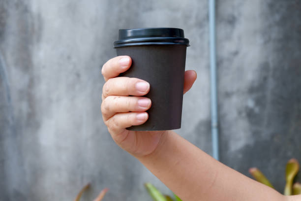 istock Black paper disposable cup for coffee in hand on a white background. natural eco packaging. 1452703743