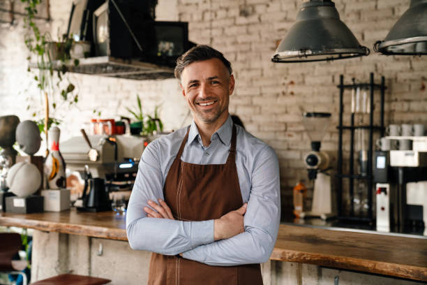 istock Adult waiter smiling and standing by bar counter while working in cafe 1452706510