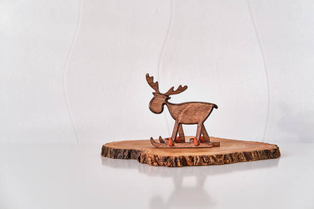 istock Christmas interior decor. Toy deer on skiing on tree cut, white wall. 1452716726