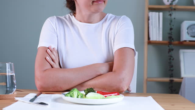 First day of diet. Unhappy young woman looking at small broccoli portion on the plate