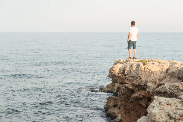 istock Man standing on mediterranean cliff at sunset. 1452719736