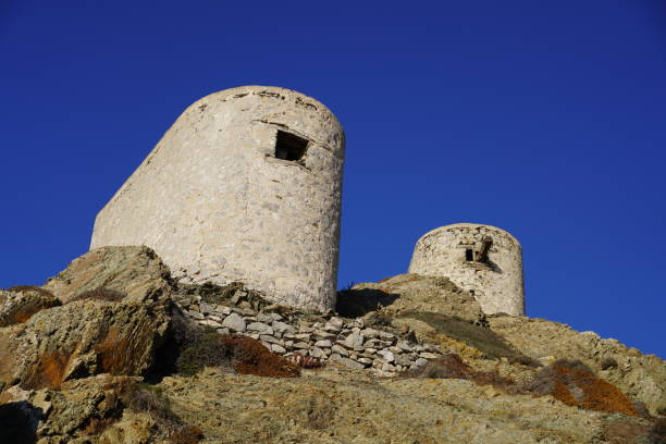 Scanned slide of a historical color photograph of three dilapidated windmills on the Greek island of Folegandros, illuminated by the orange-reddish evening or morning light of the sun