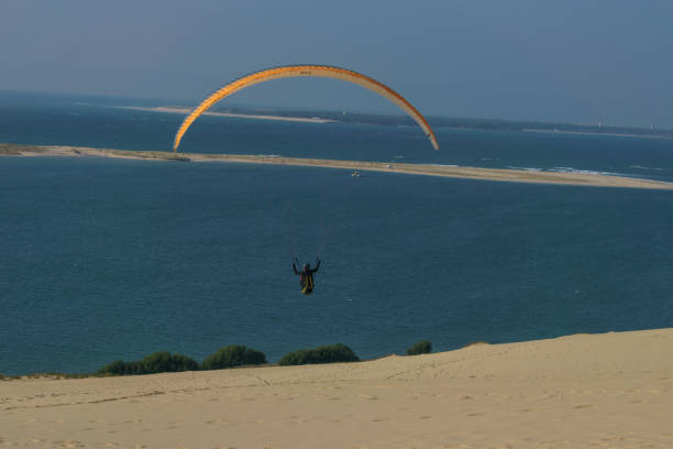 Single paraglider flying in the windy air over the dune of Pilat on a sunny day, Arcachon, Nouvelle-Aquitaine, France stock photo