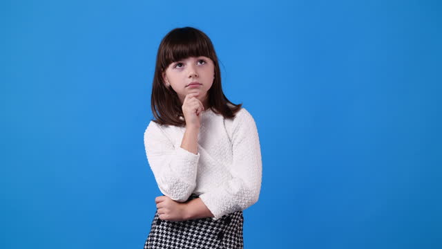 4k slow motion video of small girl thinking about something on blue background.