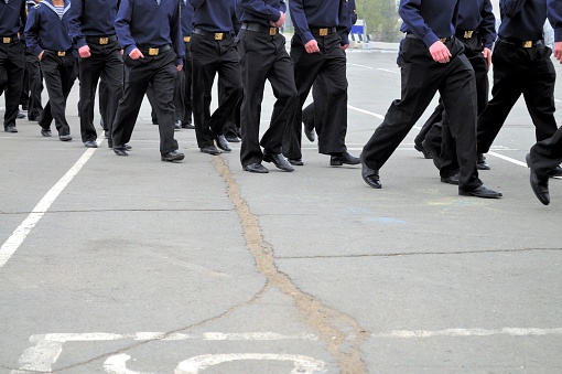 Russian sailors in uniform, marching, not in step, across a downtown street in Vladivostok.