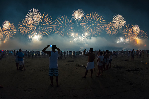 Santos city, Brazil. January 01, 2015. New Year's celebration on the beach. People watching the fireworks at the water's edge.