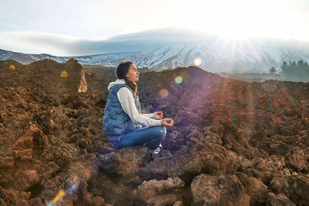 happy tourist woman enjoying freedom while meditating on lava stone at panoramic view of snowy summits of active volcano etna, tallest volcano in continental europe, sicily, italy. - high desert imagens e fotografias de stock