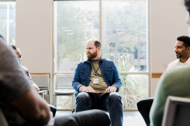 istock Male counselor watches man sharing in group therapy 1452736769