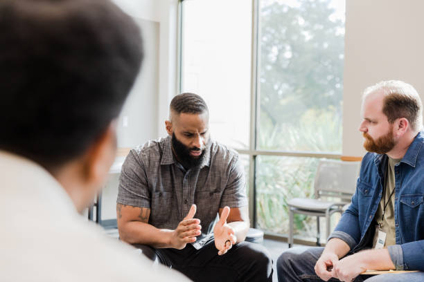 istock Man shares with diverse members of therapy group 1452736780