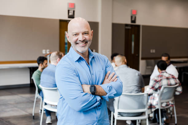 istock Confident therapist smiles for photo with men's group in background 1452736800