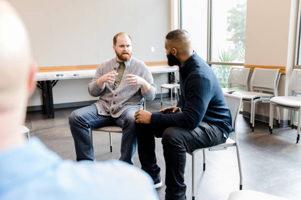 istock Over-the-shoulder view two men conversing in therapy meeting 1452736829