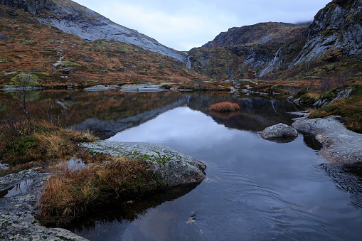In einem Bergsee bei Reine in Norwegen spiegelt sich bei bewölktem Wetter die Landschaft