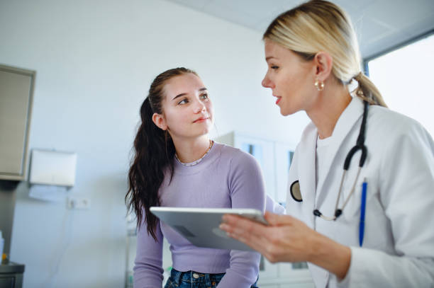 Young woman doctor explaining diagnosis to teenage girl in her ambulance. stock photo