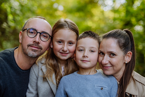 Portrait of happy family with kids in forest.