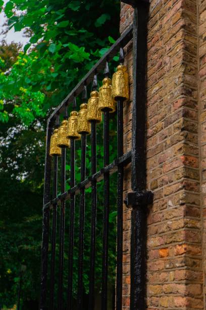 istock Vertical shot of a black gate with gold design attached to a brick wall 1452740640