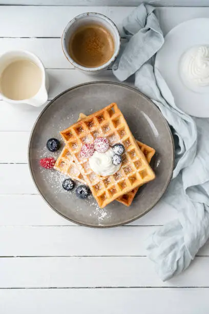 Waffles, berries and curd cheese with a cup of coffee on a wooden table