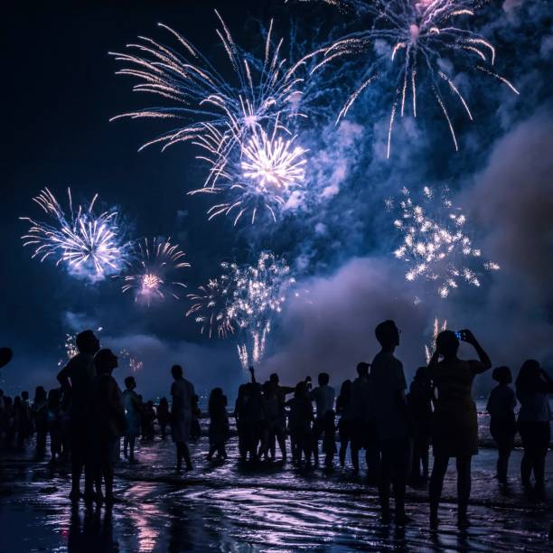 celebração de ano novo na praia. pessoas assistindo aos fogos de artifício à beira da água. - dark edge - fotografias e filmes do acervo