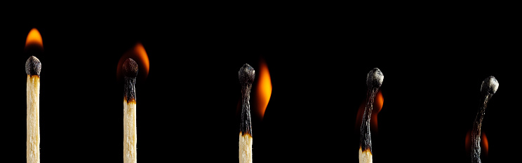 Set of lit matches of various degrees of combustion isolated on black background
