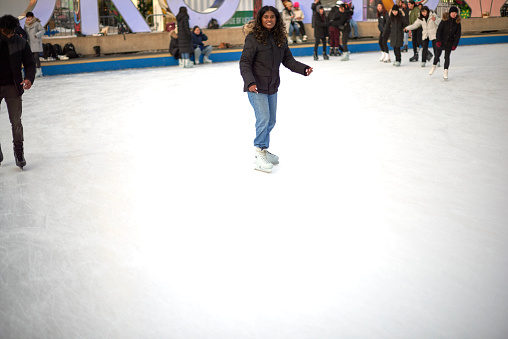Toronto, Ontario, Canada- December 14th, 2022: A black lady ice skating at Toronto City Hall’s Nathan Phillips Square.