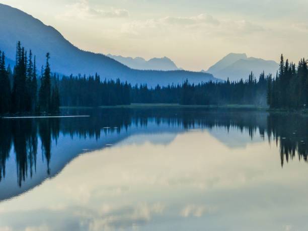 istock Beautiful view of a reflective lake surrounded by trees during sunrise 1452750437