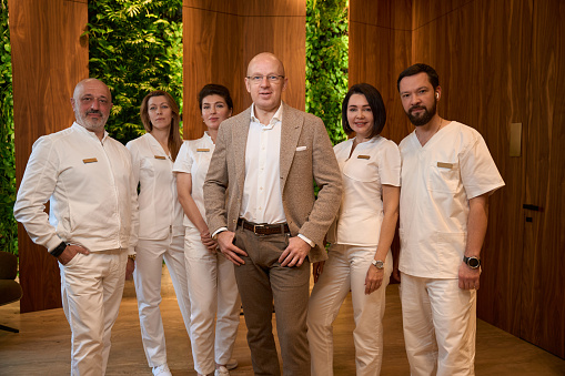 Team of doctors stands in a room with eco-design, in the center is a director in a business suit
