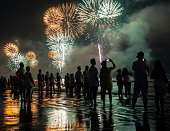 New Year's celebration on the beach. People watching the fireworks at the water's edge.