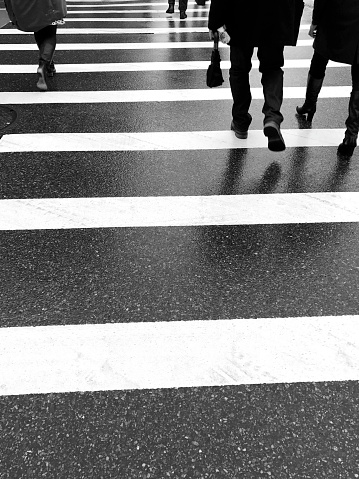 The black and white shot of the people crossing the street in New York. Manhattan pedestrians on crosswalk.