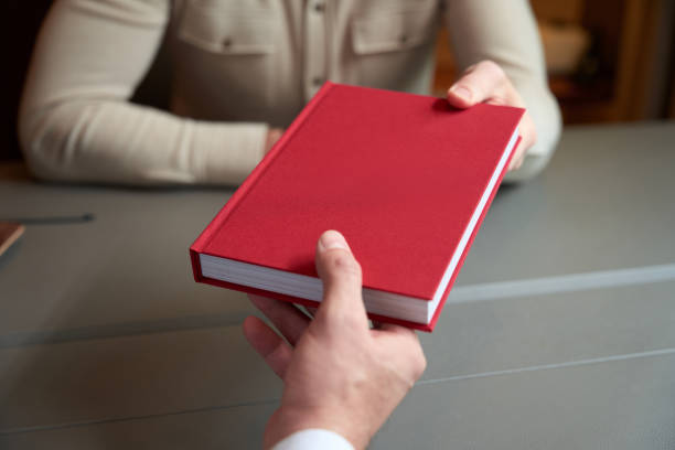 istock Man gives a red book to a colleague 1452752931