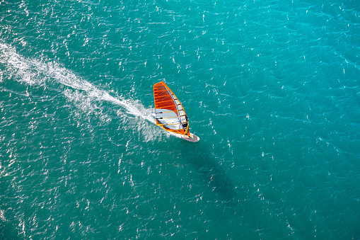 Man using windsurfing wing and a hydrofoil board while while engaging in extreme sports on the sea and ocean water. Kitesurfing.