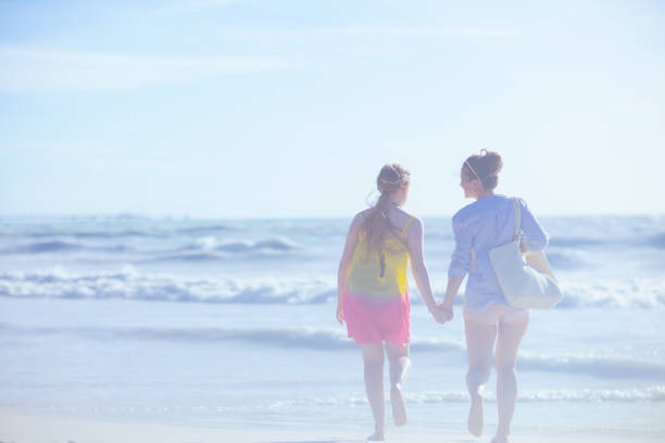 istock Seen from behind modern mother and child at beach running 1452759639