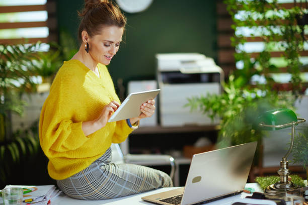 istock business owner woman in sweater in green office using tablet PC 1452759912