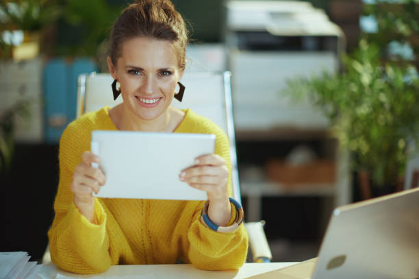 istock happy business owner woman in green office using tablet PC 1452759916