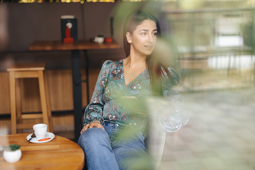 Young woman enjoying cup of coffee in coffee shop